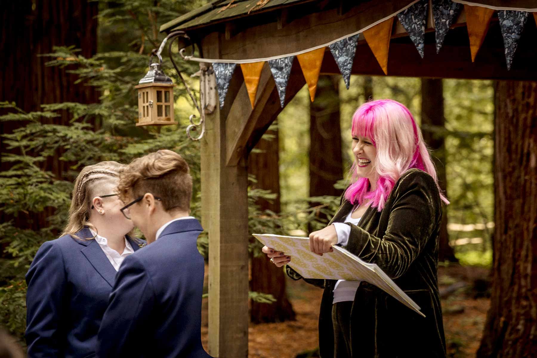 A wedding couple and their celebrant laugh during their personalised ceremony in Pulborough, West Sussex
