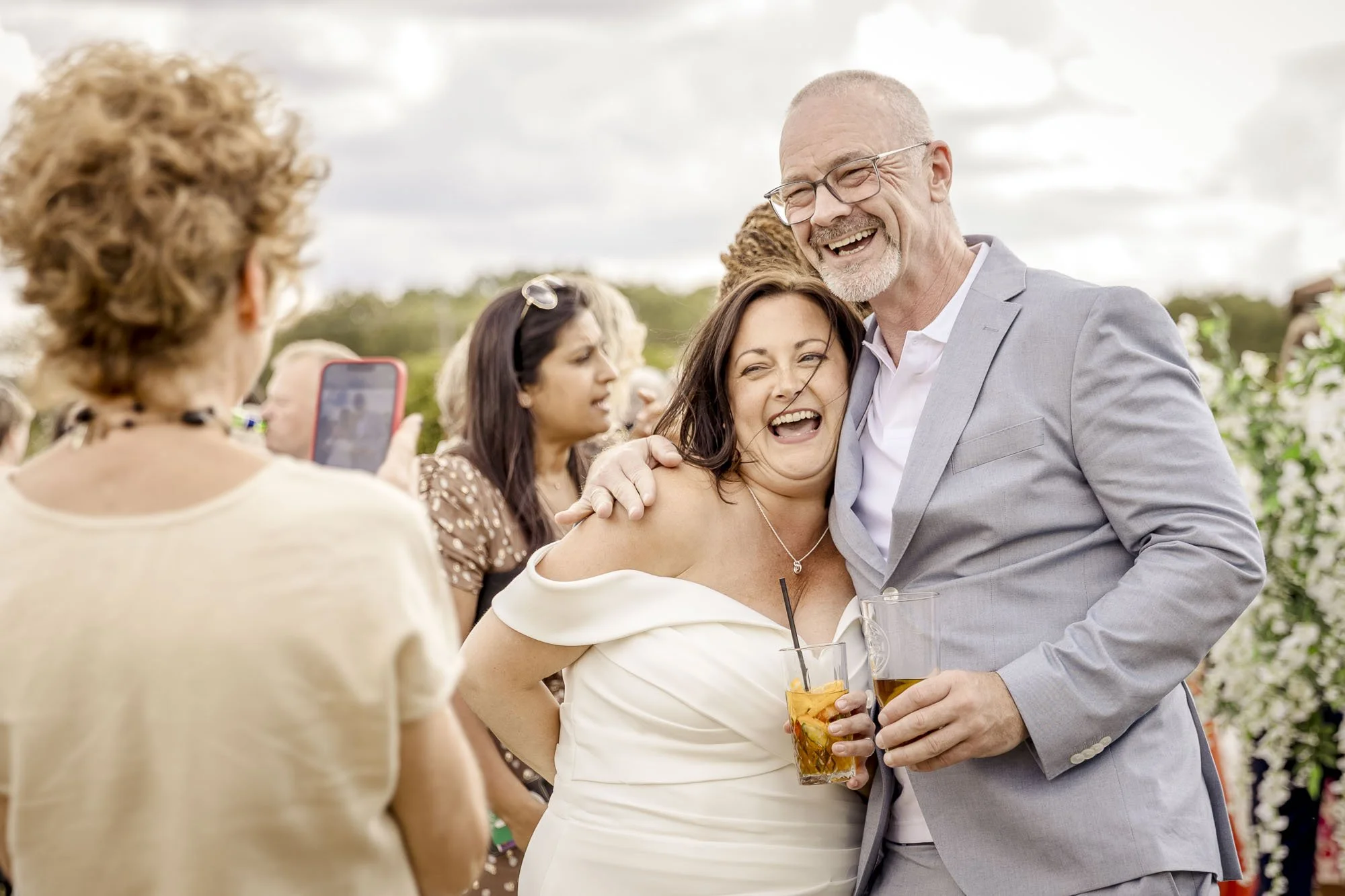 Bride in a white dress laughing with a guest whilst having their picture taken at her Leicestershire wedding at Badgers Mount