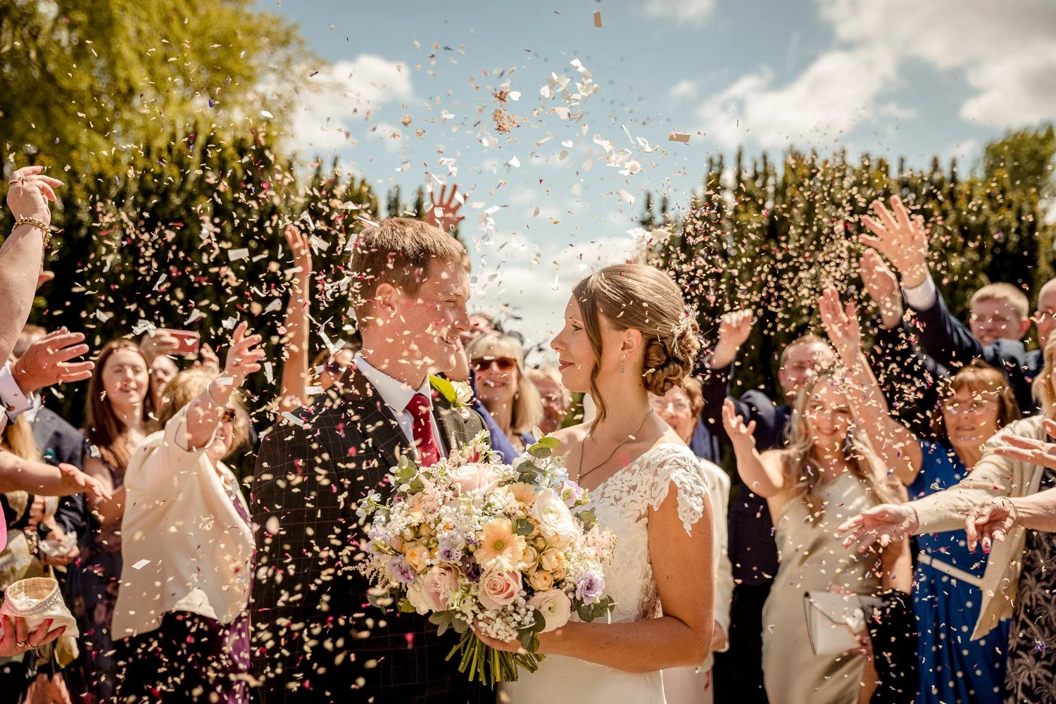 Bride and groom with confetti and guests at Cathorpe Manor