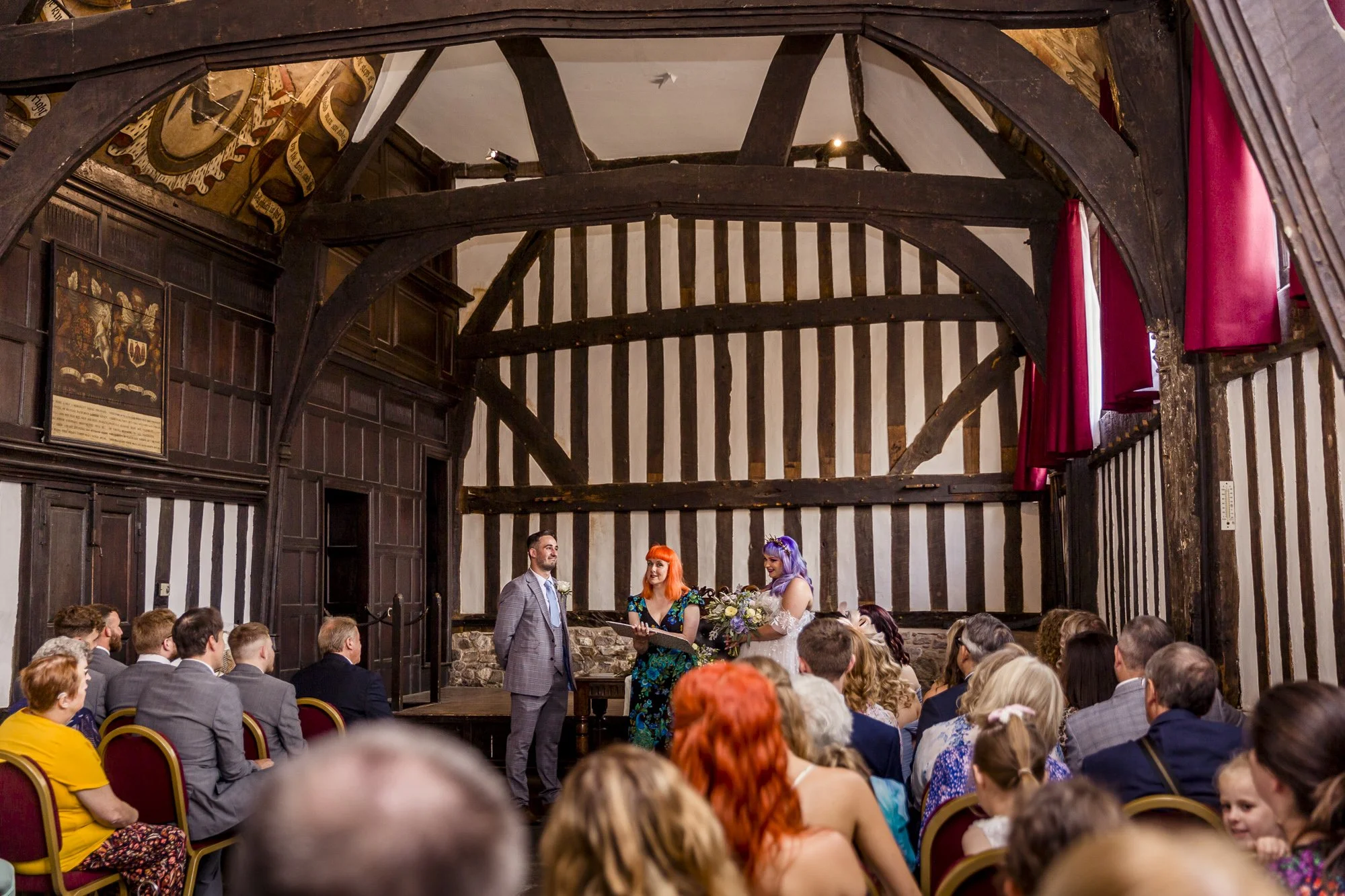 A celebrant with orange hair leads a wedding ceremony in Leicester's historic Guildhall