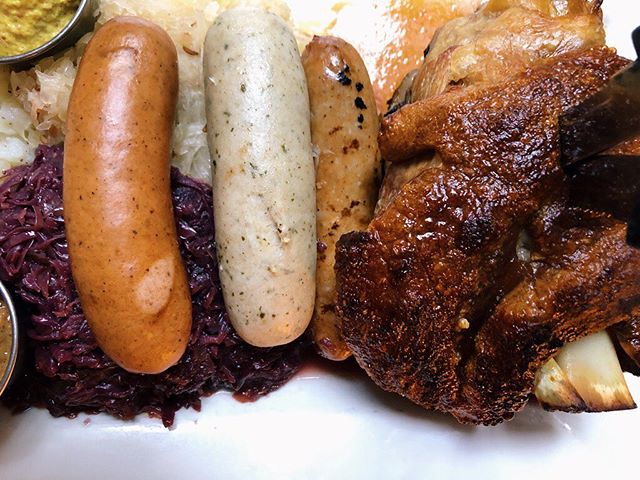 Up close and personal with the pork shank platter. Our famous schweinhaxe, a trio of sausages all atop a bed of red cabbage and sauerkraut. Delicious is an understatement.
#germanfood 
#gutenappetit 
#lecker