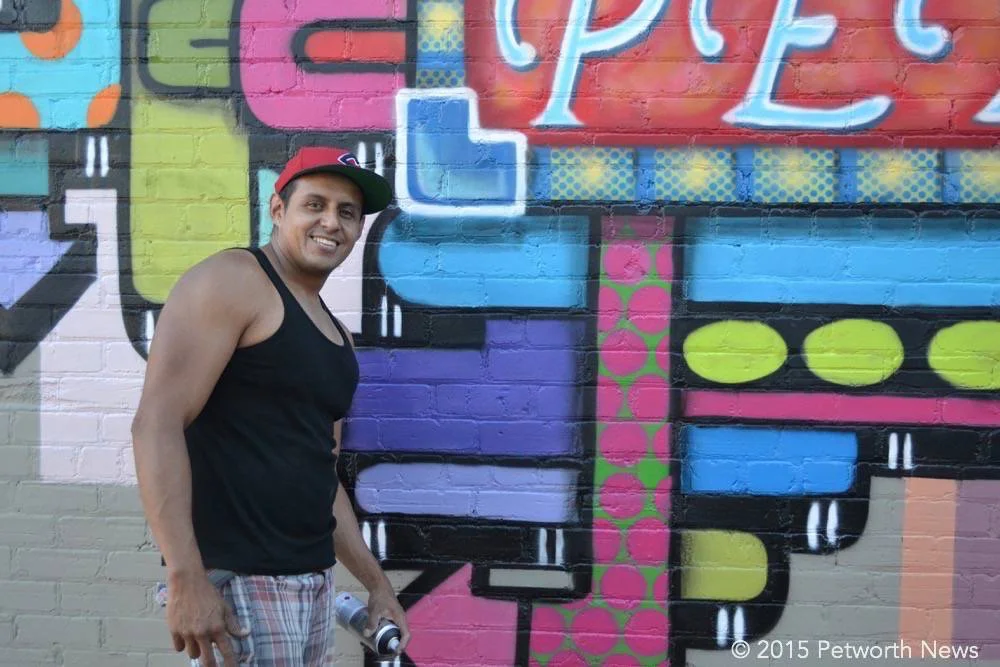 Artist Juan Pineda poses next to the almost-finished mural.