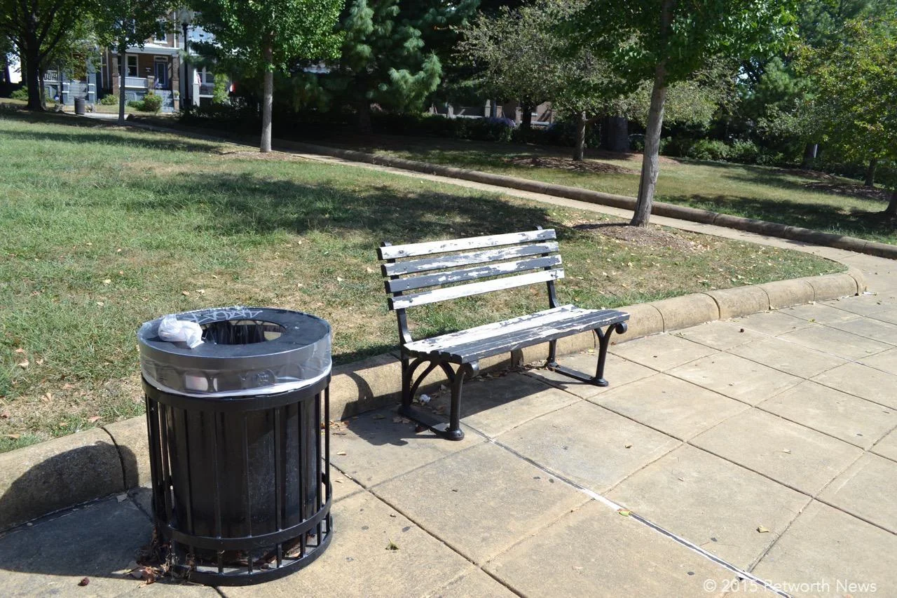 A trash can with graffiti and a bench that's crying out for some paint
