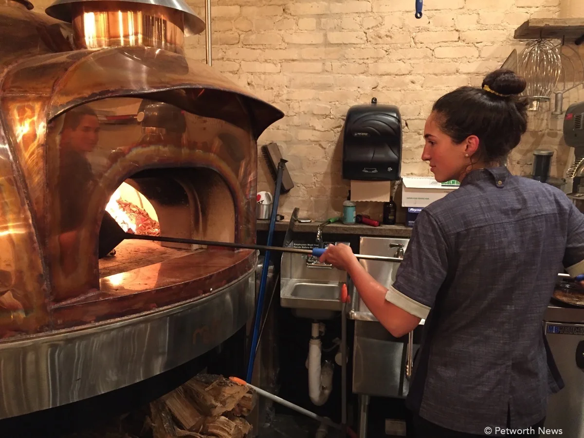 Dani Moreira taking a pizza out of the wood oven at Timber Pizza.