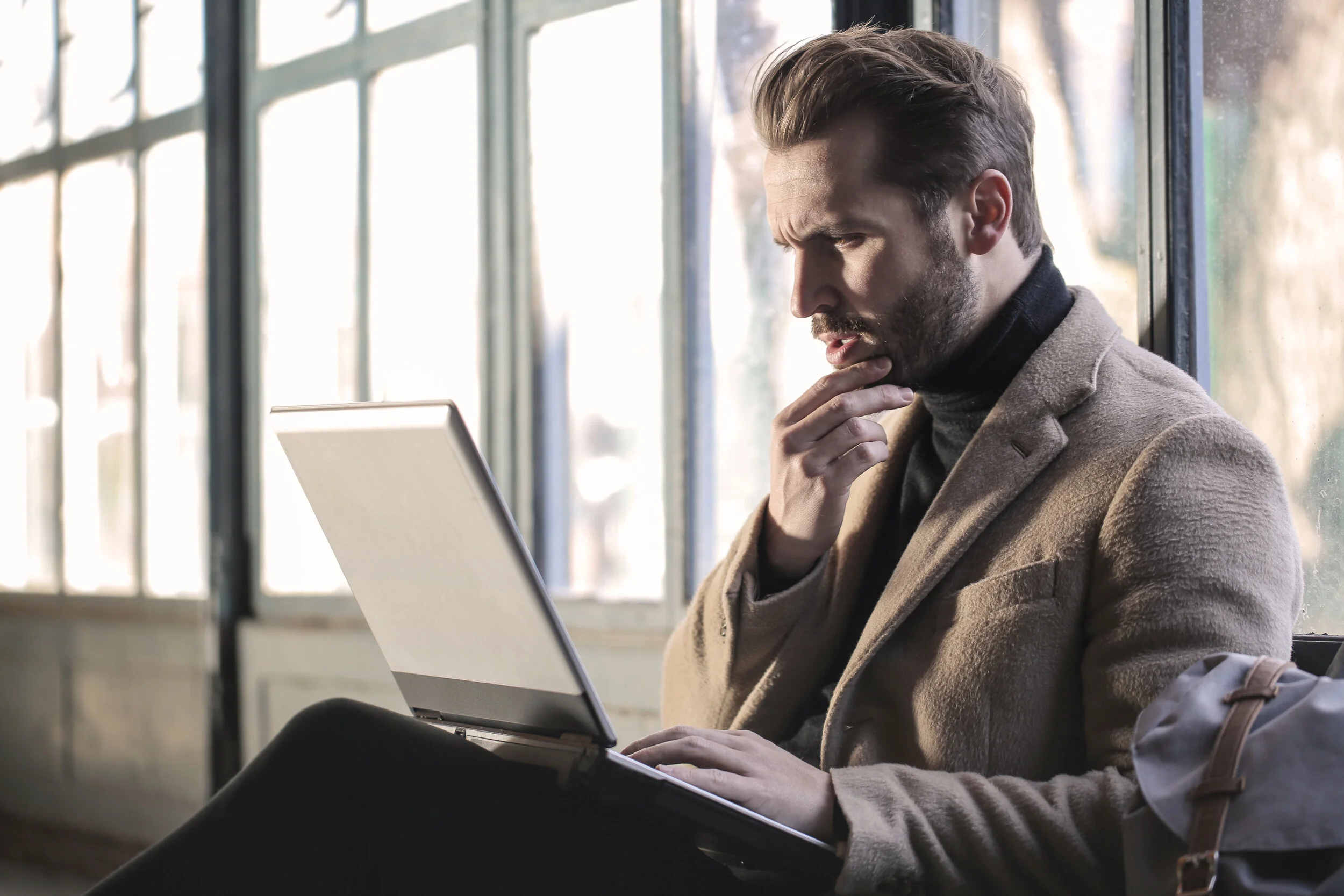 Some photo of a random guy looking perplexed using a computer.