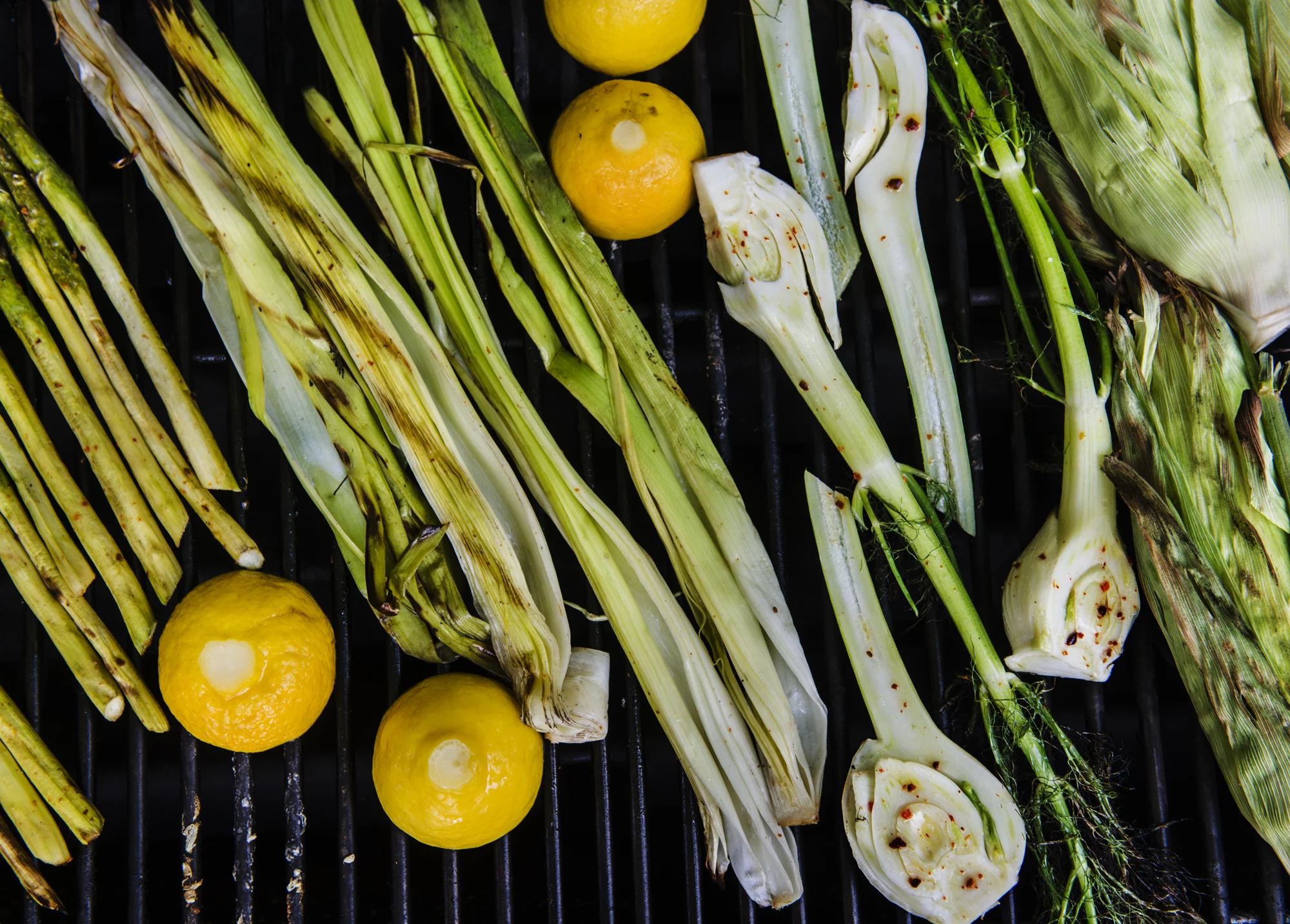 The first step in preparing the vegetables is to ready them for the grill. The is corn is cooked with the husk on to impart the flavor of the char-roasting husks into the fresh and delicate kernels of sweet just picked corn, without scorching or drying them out. This is done by carefully pulling back each leaf, leaving them attached to the cob. Once accomplished, remove the silk. Delicately smooth the husk leaves back to their original positions on the cob. Soaking the cobs in water, restored of their husks, will prevent too much burning, allowing the sweet kernels to steam to perfect tender juiciness. The leeks are split in half or quarts lengthwise, depending on their girth, to allow washing of their sandy interiors. The fennel bulbs, stems and fronds are also sliced lengthwise into halves, quarters or eighths, depending on their bulb circumference, for even cooking. The asparagus are trimmed of the woody ends of their stalks for even cooking and tender eating. If they are very large asparagus, they will need an additional pairing, with a vegetable peeler, of the thickest part of the ends.