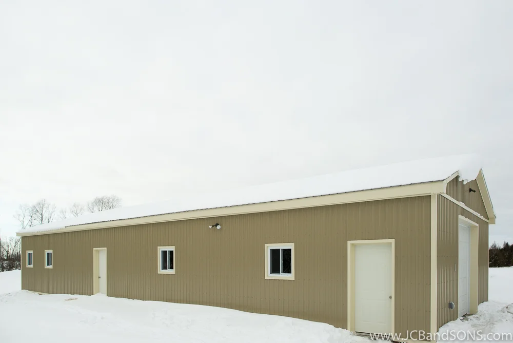 Completed side view of honey shed in Southgate showing tan steel cladding, cream trim details, and steel roofing on custom-built addition for apiary use.