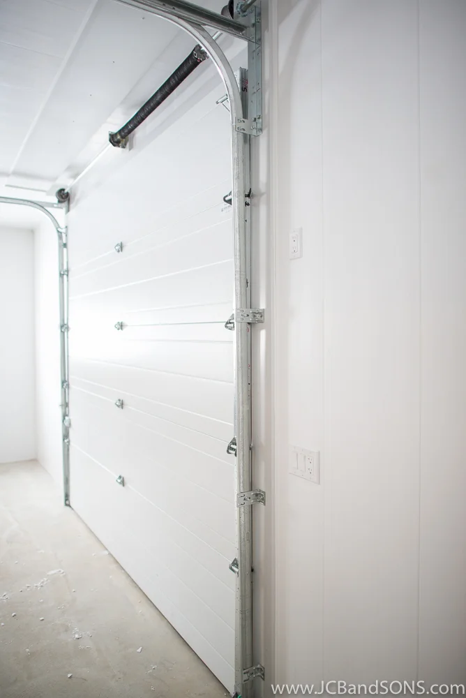 Side view of white overhead door in Southgate honey shed showing clean installation and door hardware detail against Trusscore wall panels.