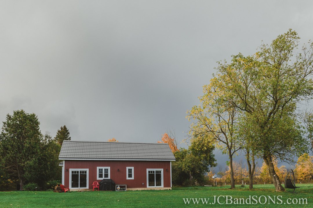 Completed red siding and white vinyl windows installed on rear addition to log home in West Grey