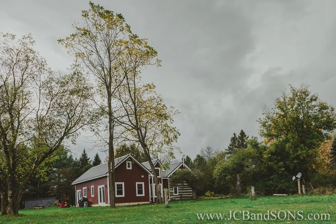 Completed rear view of completed addition on heritage log home near Priceville with red siding and white vinyl windows