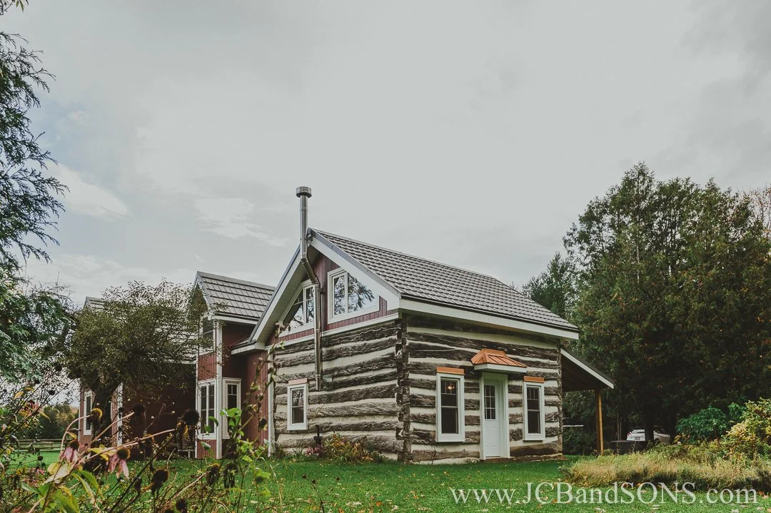 Evening glow on completed red siding and white-trimmed windows of completed heritage log home addition