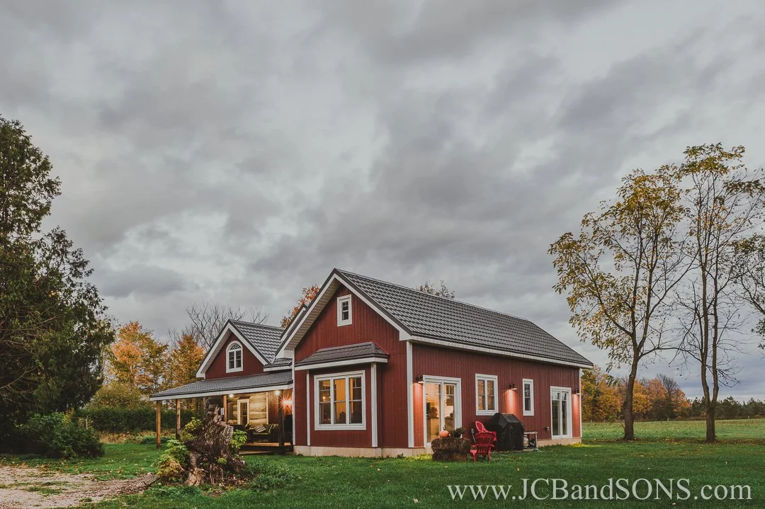 Completed rear addition to log home featuring white soffit and fascia, energy-efficient windows, and clean trim lines