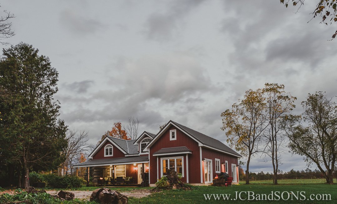 Completed evening shot of back addition to log home in West Grey showing exterior lights and new white trim