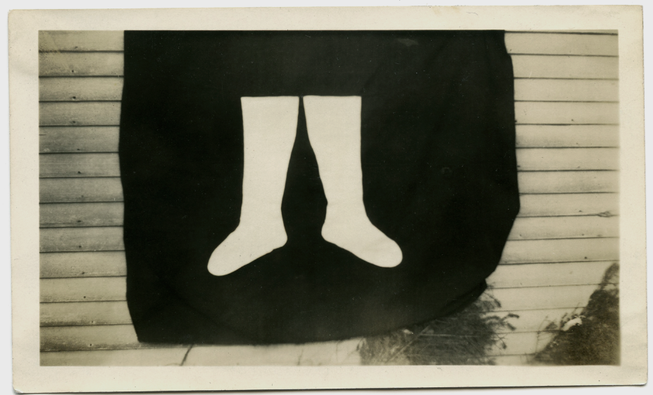 The pride of knitting a new pair of knee length white socks is apparent by the fact that they set up this backdrop outside to photograph them. c. 1915