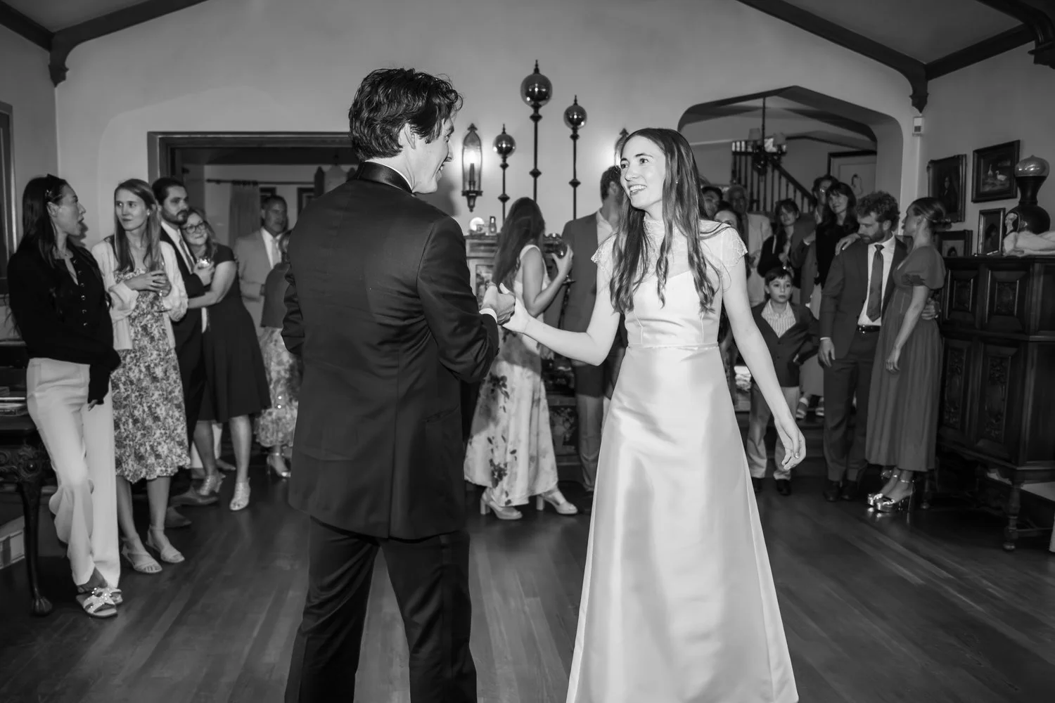 A couple dancing at a wedding reception, with guests watching in a decorated indoor space.
