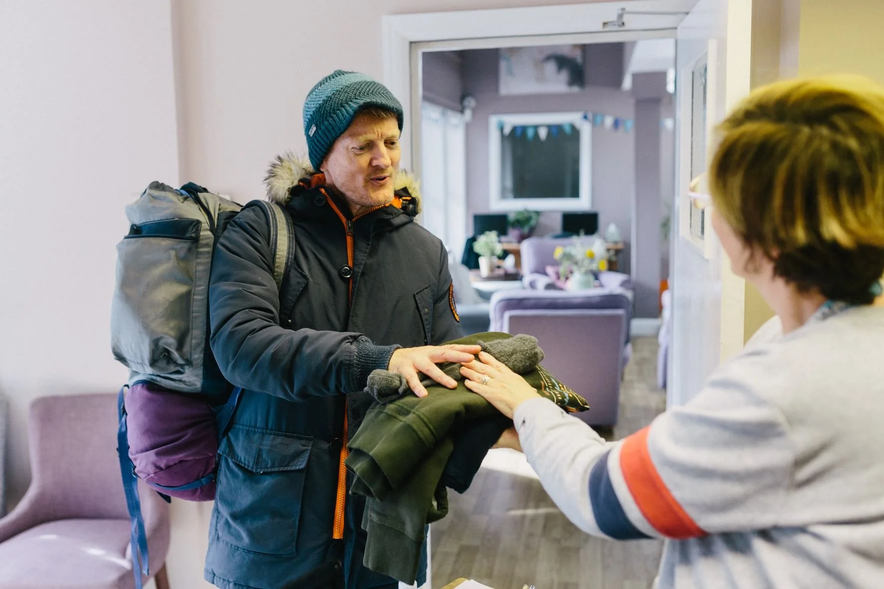 Service user at the Haven drop-in collecting his clean washing from a member of New Hope staff