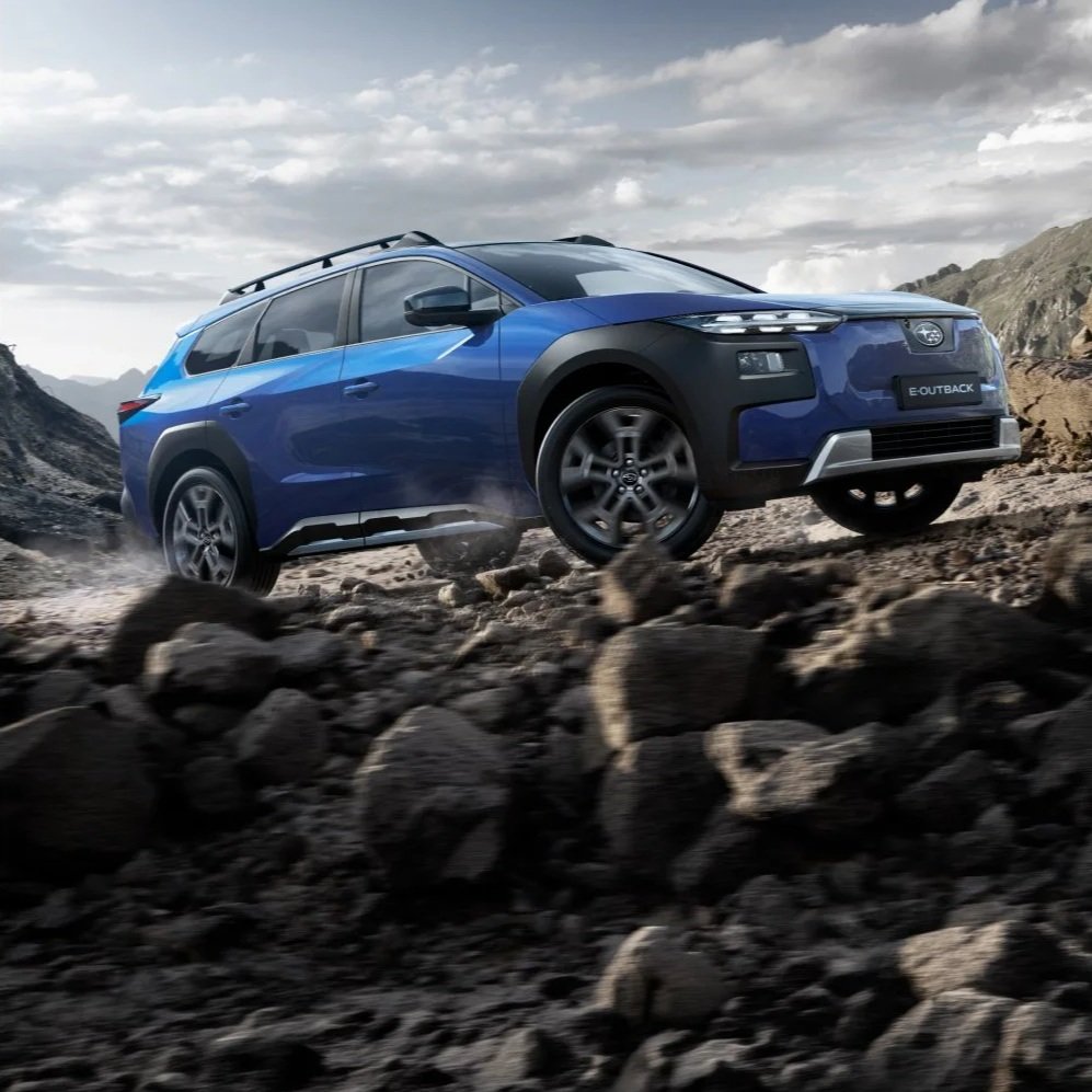 En blå Subaru Outback kjører på steinete terreng i en fjellandskap