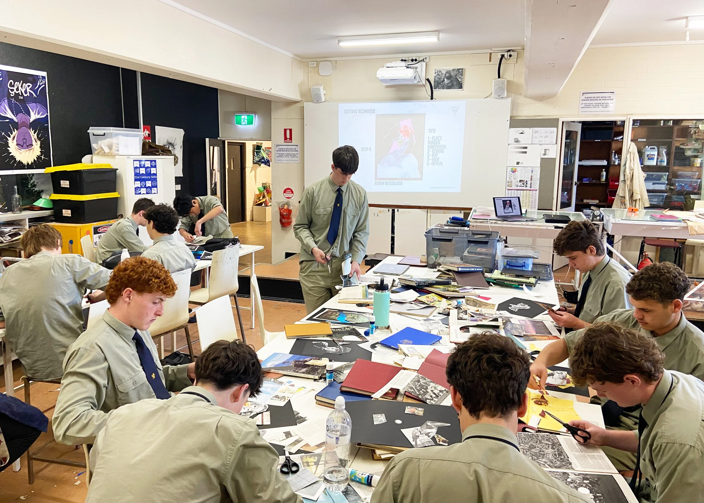 Scots college students working on collage in a classroom with art supplies, books, and a presentation projected on the whiteboard.
