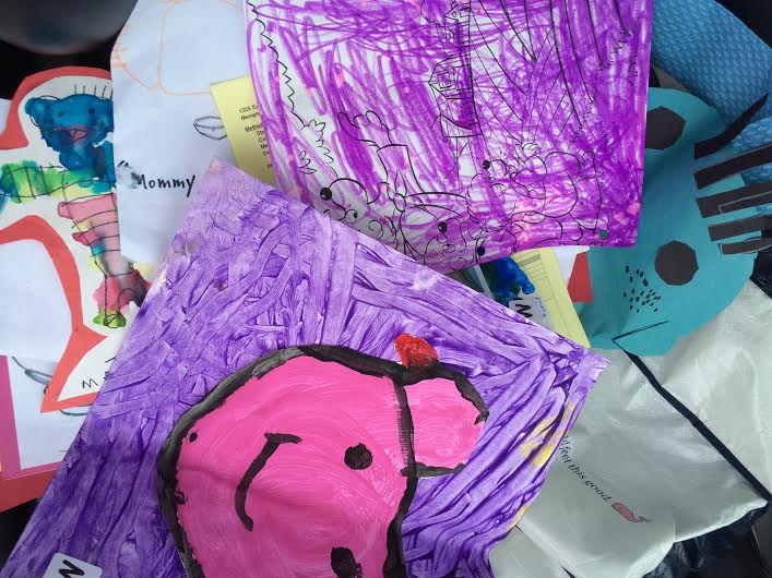 (My front car seat yesterday after combining the 1.5 year old and 4 year old's artwork haul from school.)