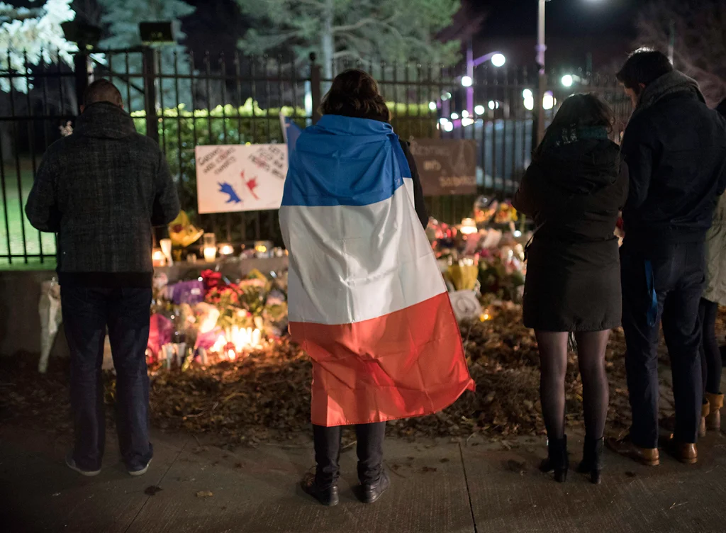 A person wears a French flag at a memorial outside the French Embassy, Saturday, Nov. 14, 2015, in Ottawa, Ontario, following deadly attacks in Paris on Friday. Photo by Justin Tang/The Canadian Press via AP