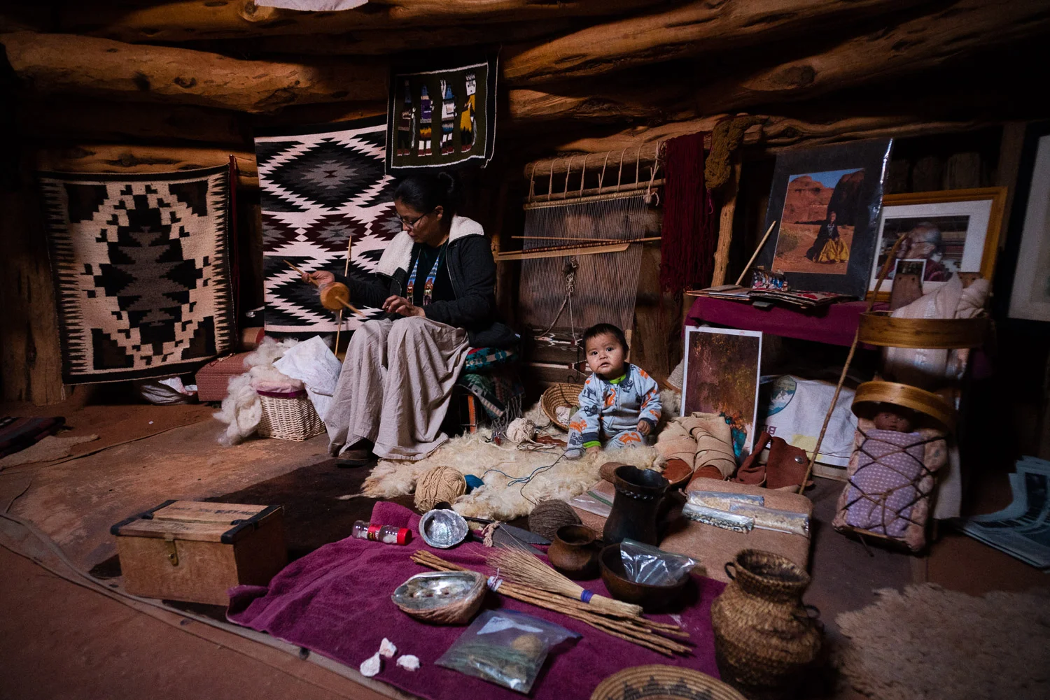 Inside the hogan, a woman works on traditional crafts while her child chills out on what looked like a comfy sheep skin.