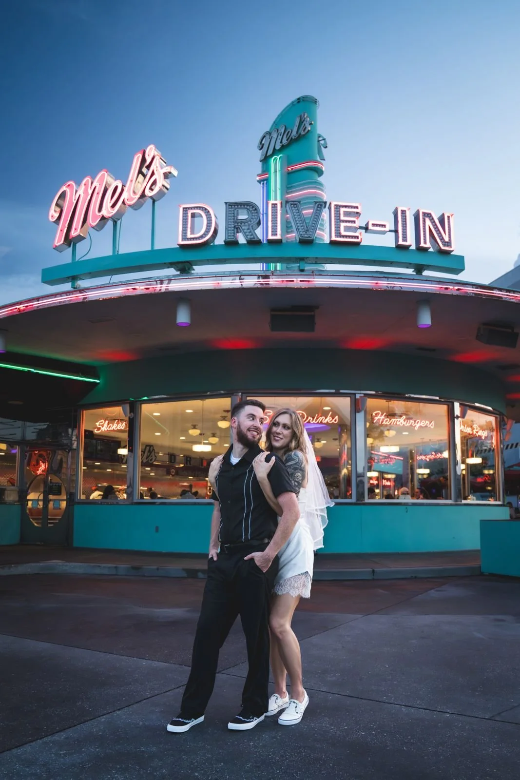 Couple posing at the Mel's Drive-In neon sign at dusk, Universal Studios Florida