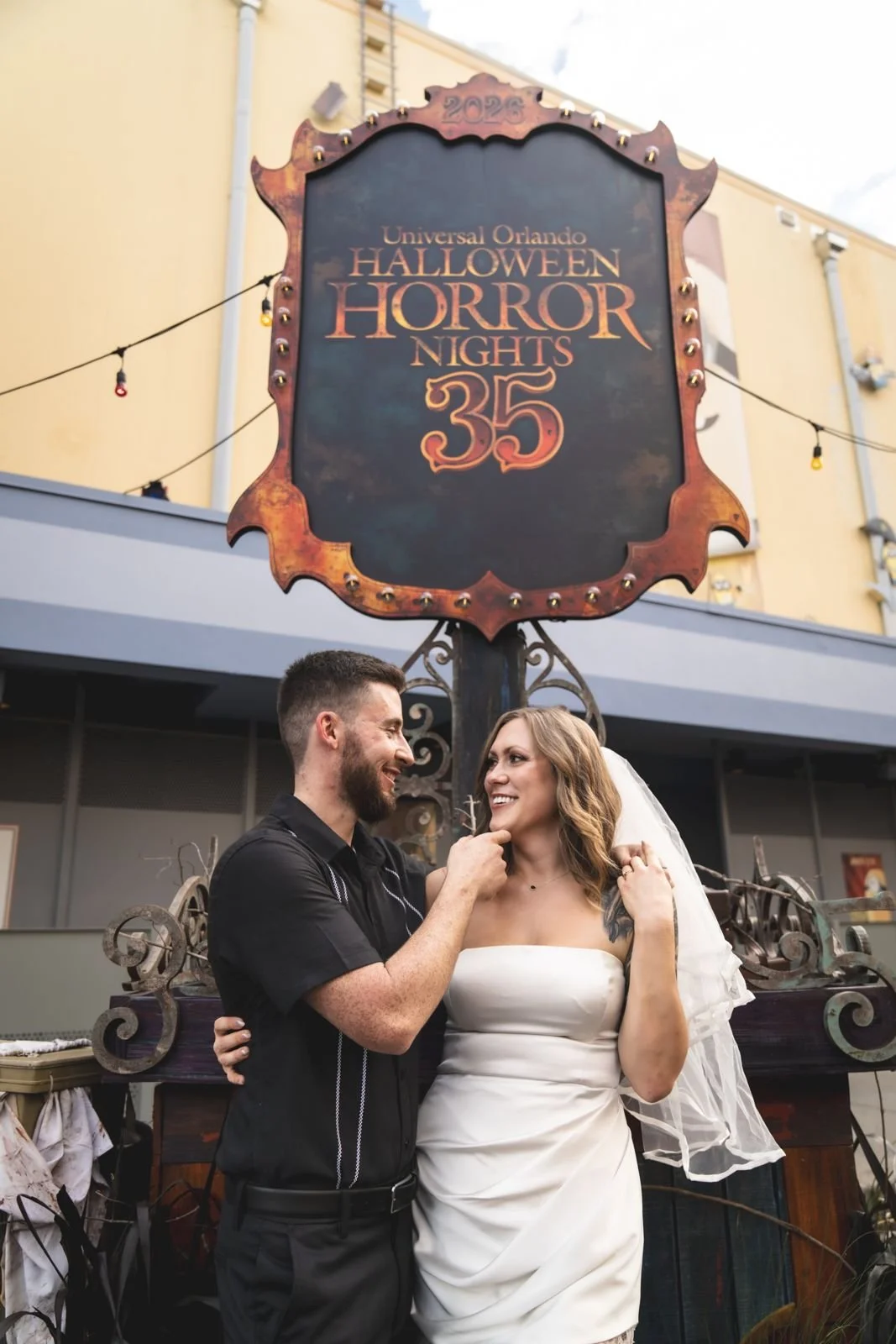 Couple smiling under the framed Halloween Horror Nights 35 sign at Universal Orlando