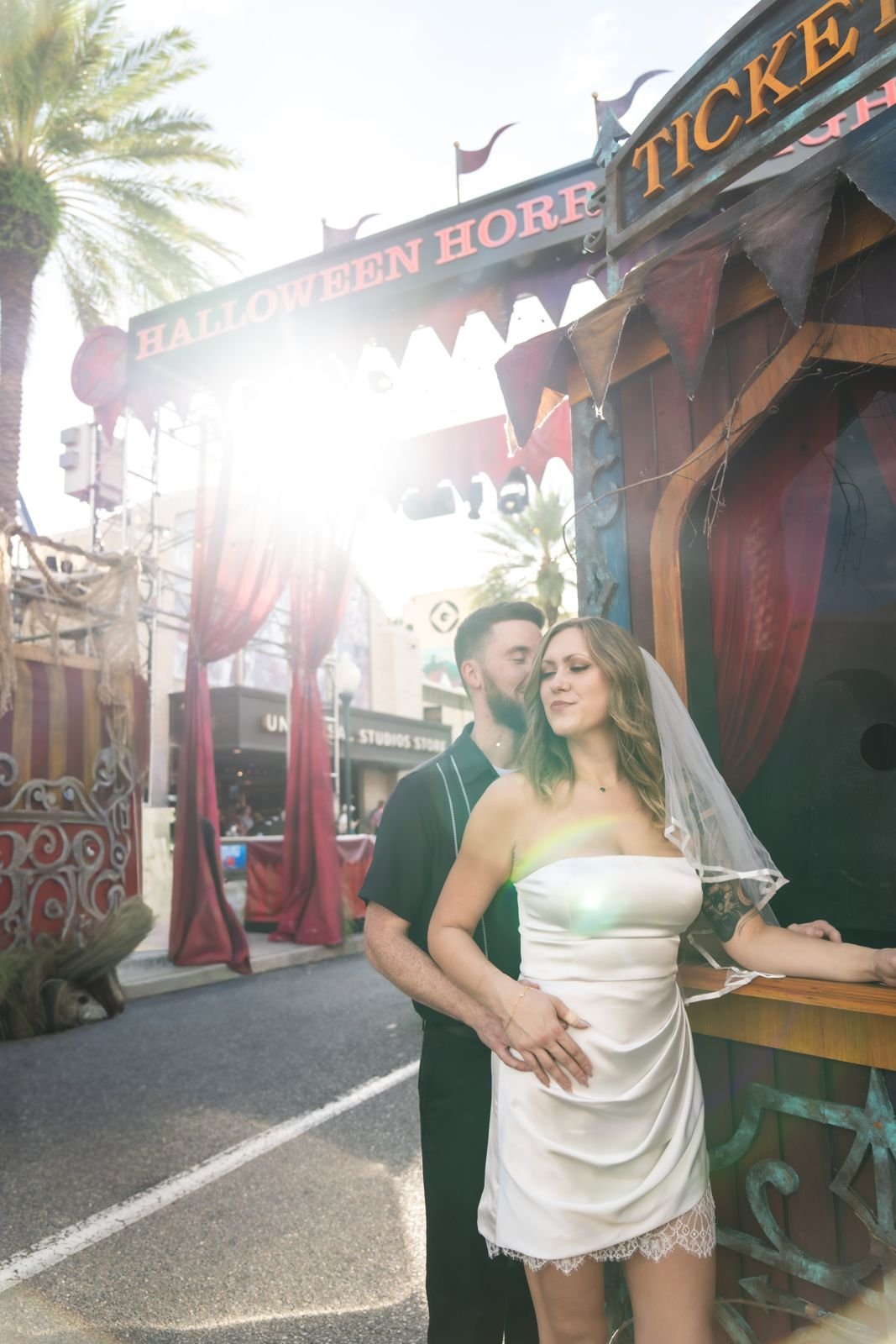 Groom kissing the bride by the Halloween Horror Nights ticket booth in golden hour sun, Universal Orlando