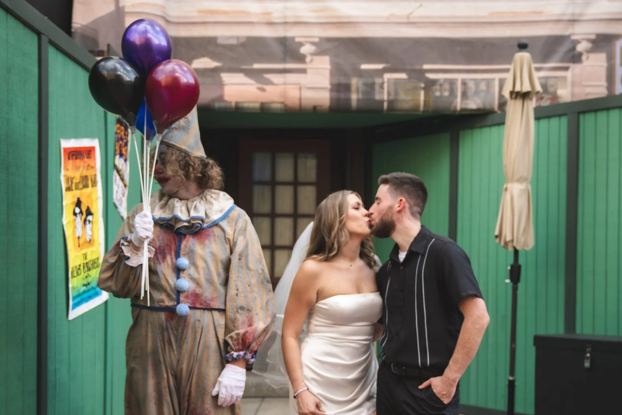 Couple kissing beside a clown scare actor holding balloons at Halloween Horror Nights 35, Universal Orlando