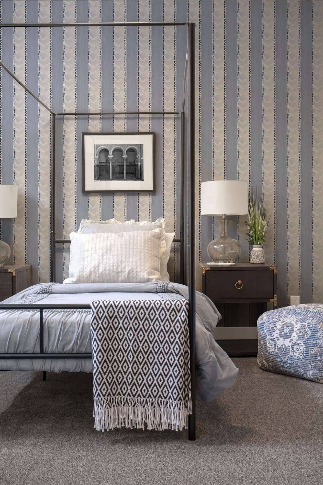 New Traditional design melds the classics with approachable, and livable, and that's just what this Guest Room offers. The four-poster bed in modern materials, the campaign chest, and the fresh take on striped wallpaper all create a welcoming space.
