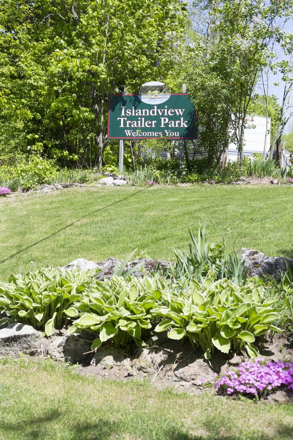Sign for Islandview Trailer Park surrounded by lush green trees and plants.