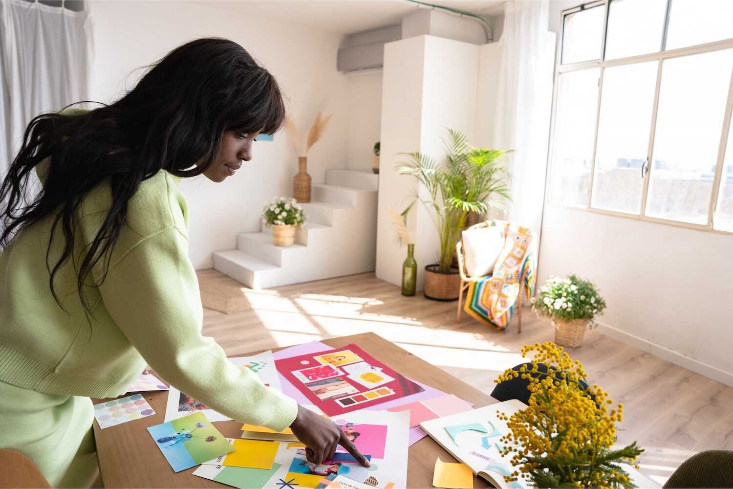 Affirmations for Creativity: Woman creating a colorful vision board in a bright, inspiring home workspace filled with natural light and plants.