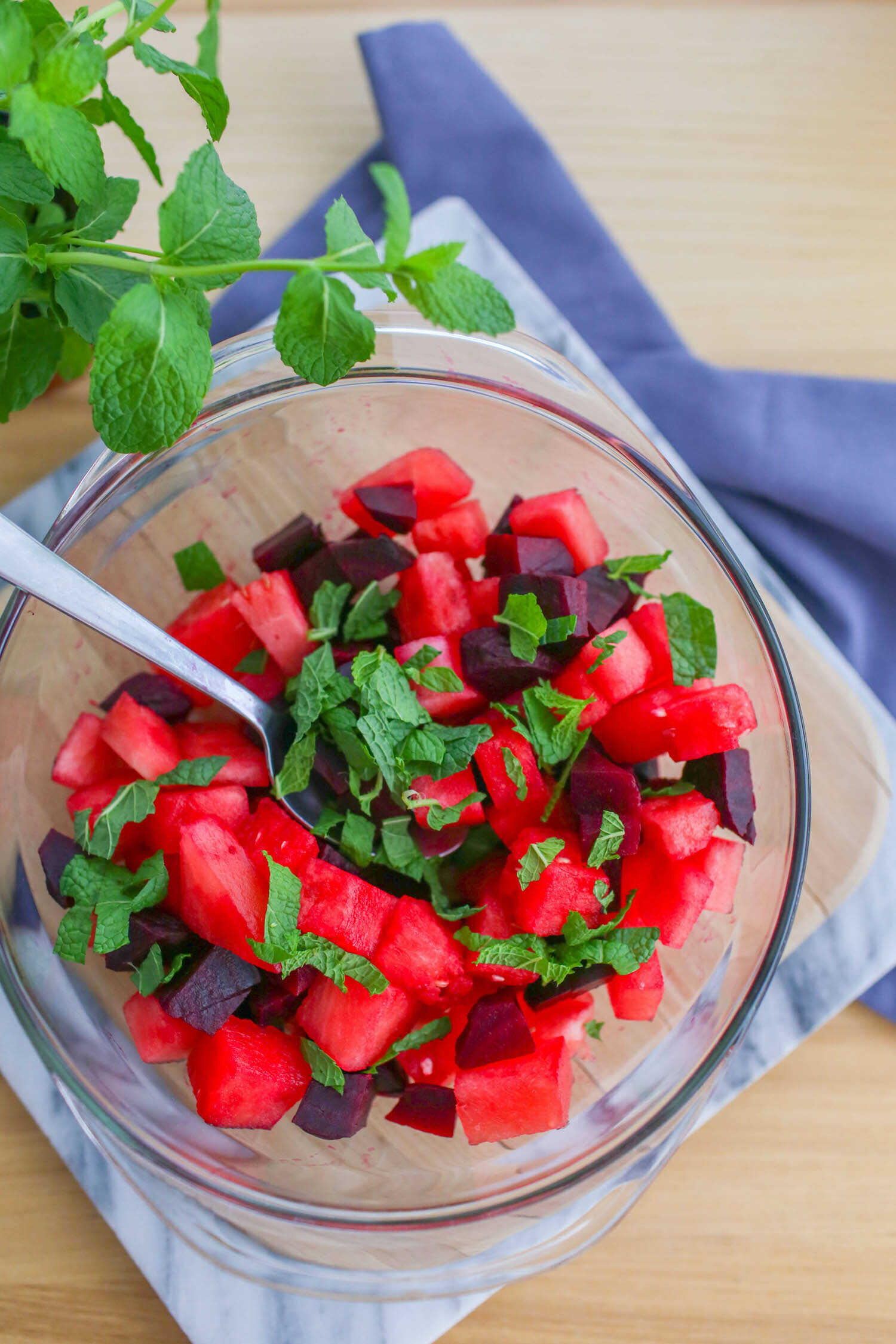 Fresh chopped mint added to salad bowl with watermelon and beets.