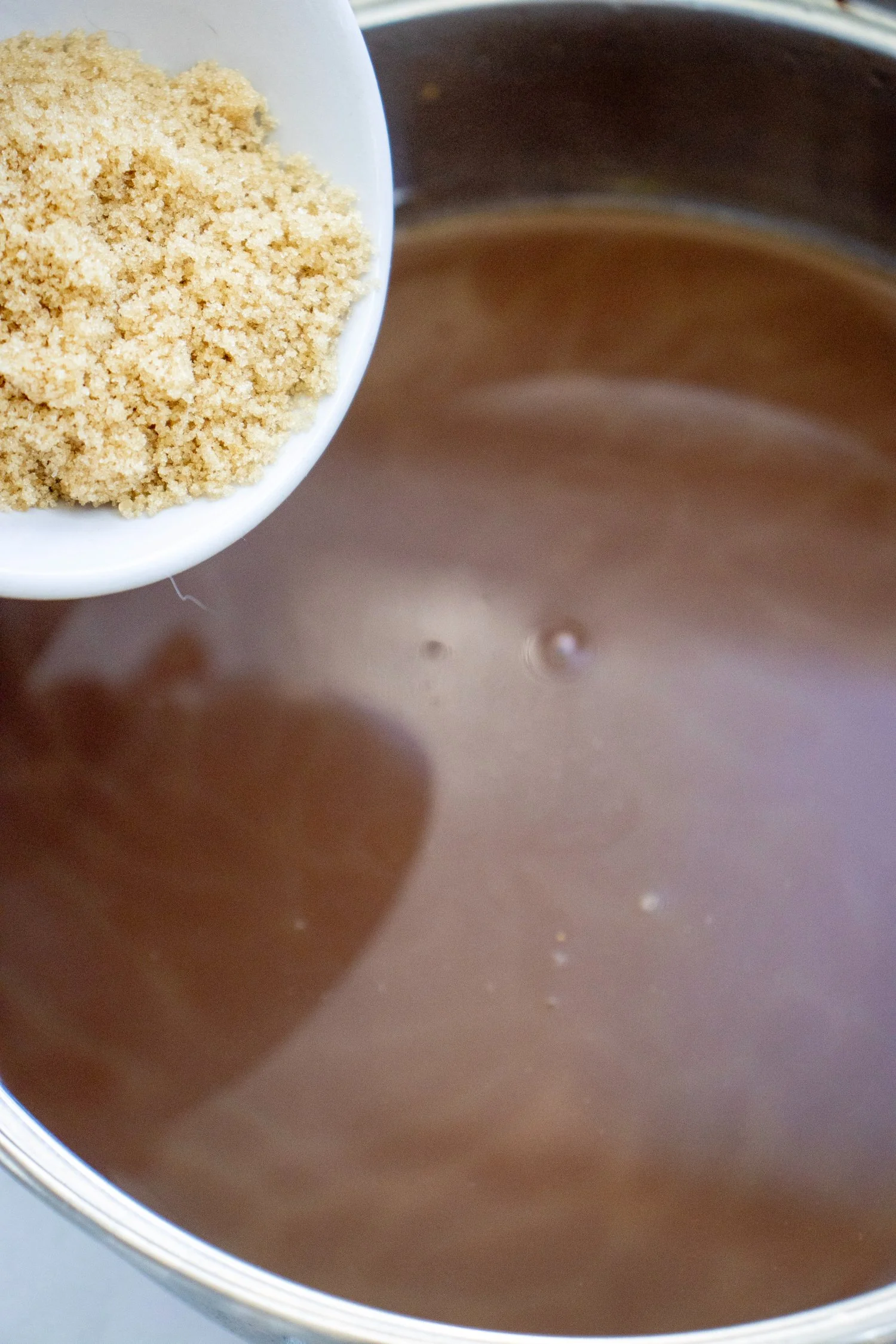 Pumpkin Spice Hot Chocolate being sweetened with brown sugar in a saucepan for an easy homemade fall drink.