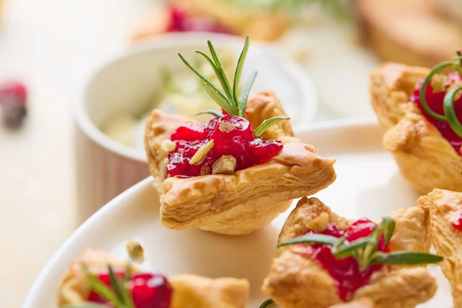 Holiday Heaven Bites made with flaky puff pastry, creamy Brie cheese, cranberry sauce, and fresh rosemary garnish on a serving platter.
