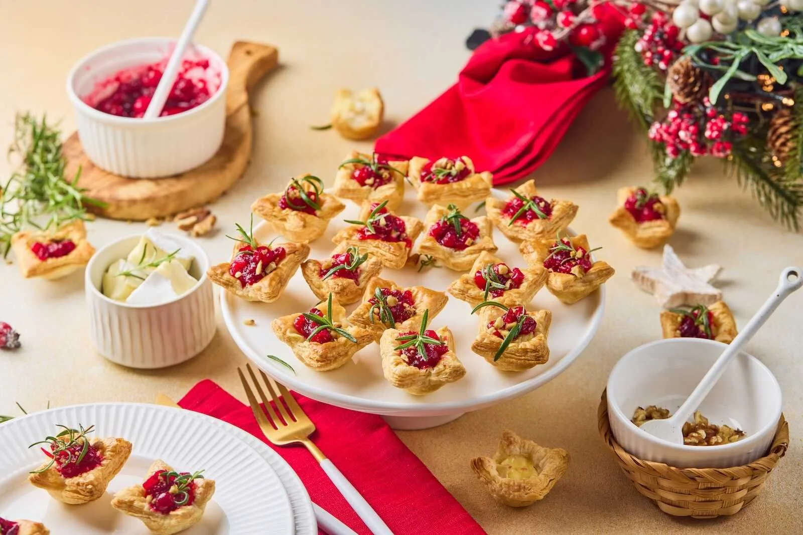 Holiday Heaven Bites arranged on a festive serving platter with flaky puff pastry, creamy Brie cheese, homemade cranberry topping, chopped walnuts, and fresh rosemary for a holiday appetizer.