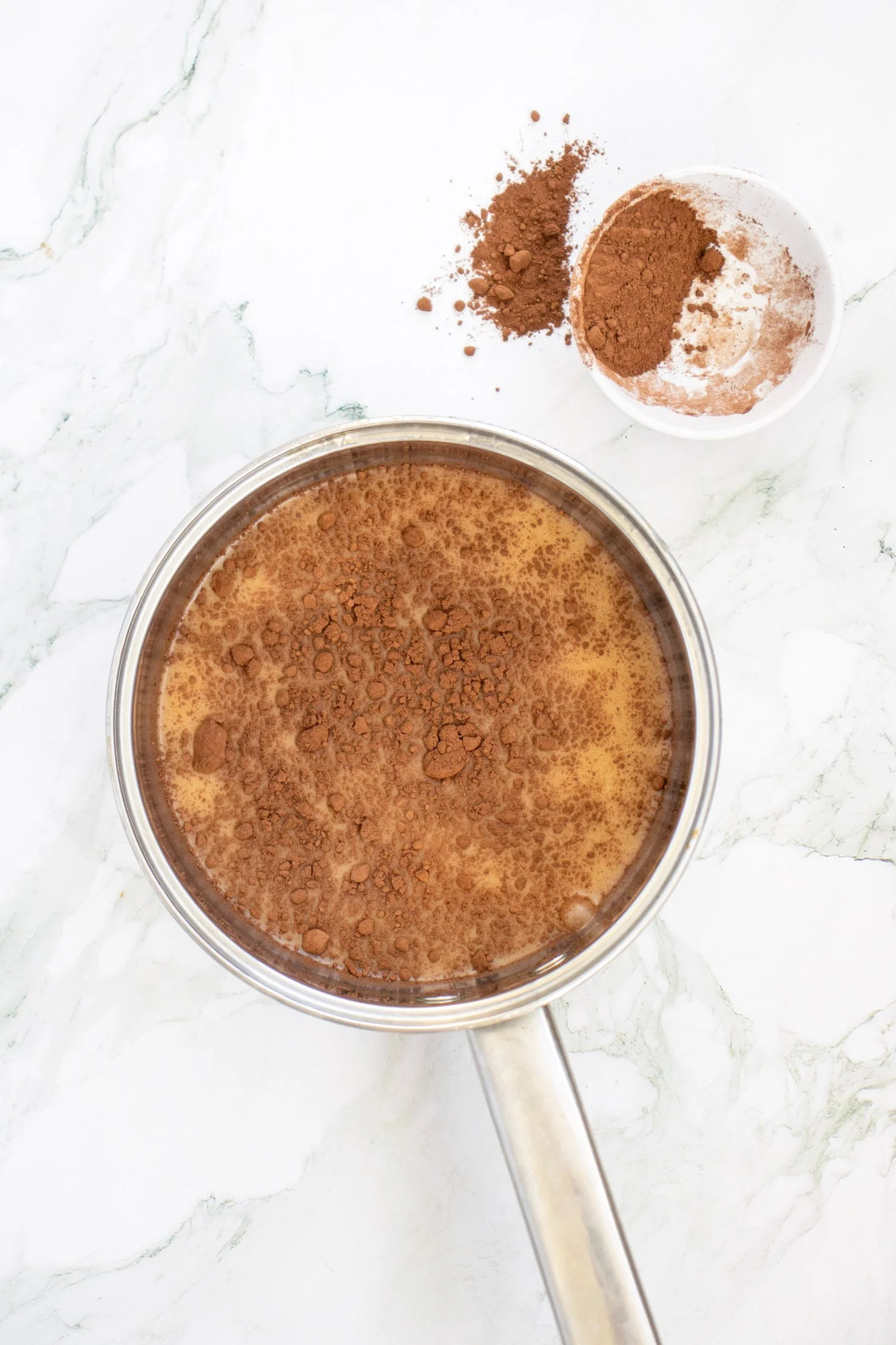 Pumpkin Spice Hot Chocolate ingredients combined in a saucepan with cocoa powder, ready to be whisked and heated.
