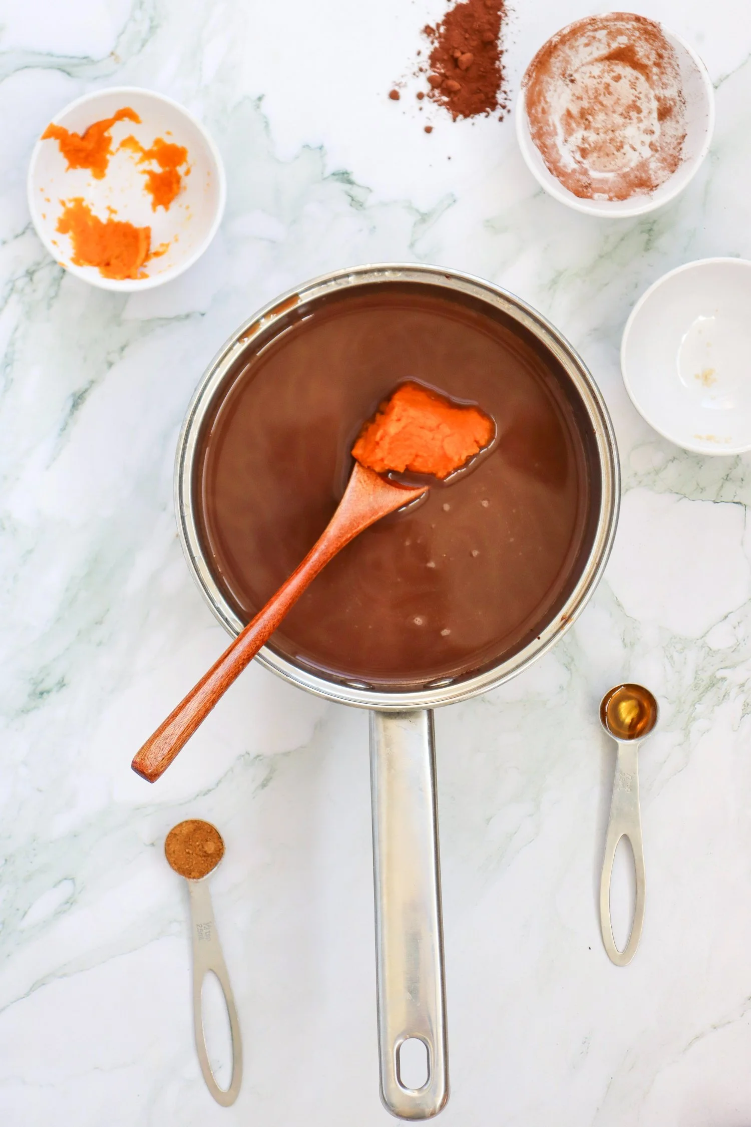 Pumpkin Spice Hot Chocolate with pumpkin puree being added to a rich chocolate mixture in a saucepan for a cozy fall drink.