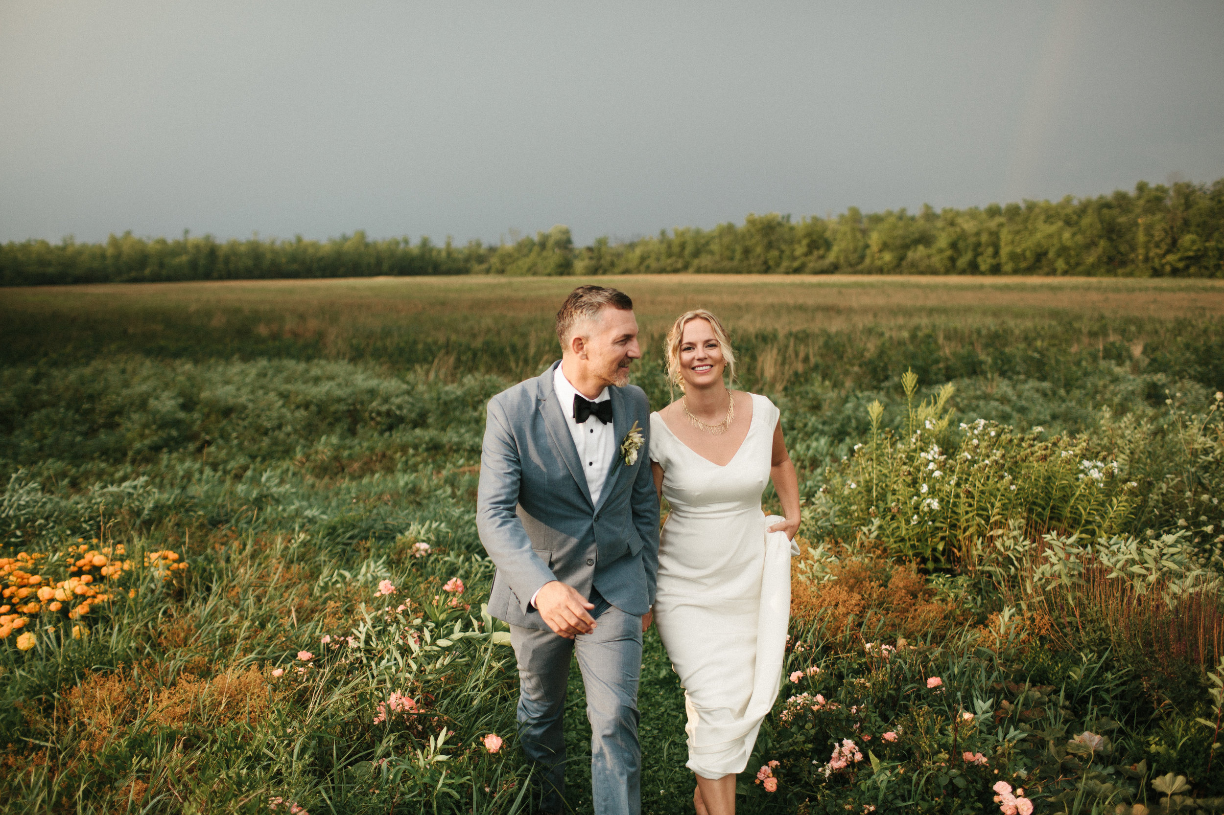  Bride and groom walking in a field of flowers in New York. 