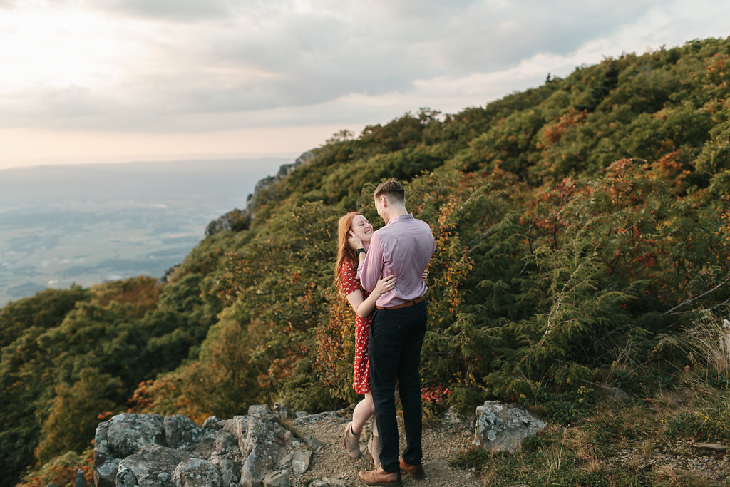  Engaged couple kissing on cliff in Shenandoah National Park. 
