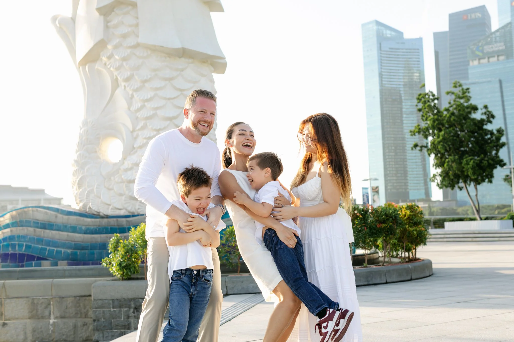 family playing and hugging around Merlion