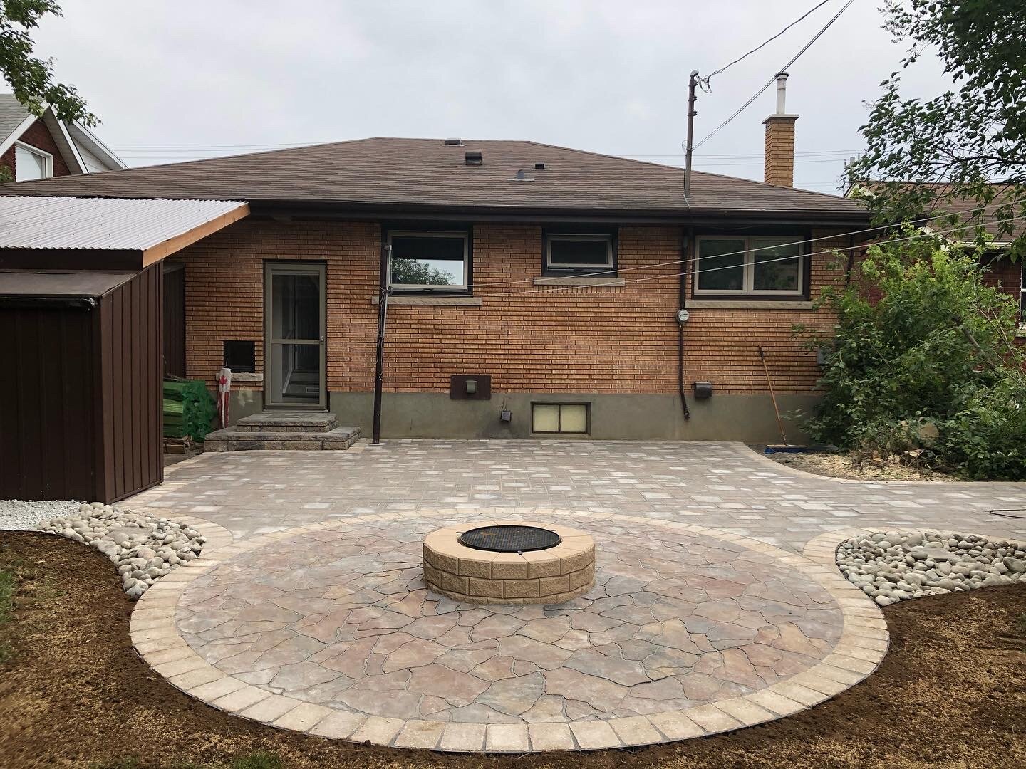 Flagstone Circle Patio Fire pit area, with a Verano paver patio furniture area, tied in with a roman paver border throughout, river rock planter beds and a stone step 