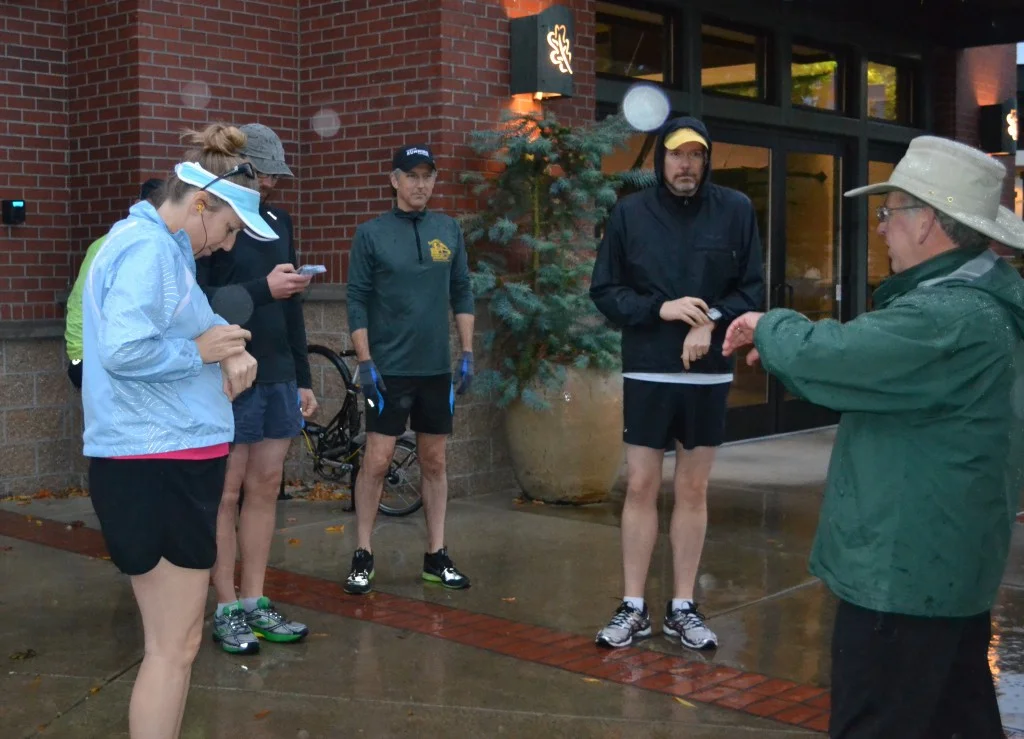  Rhonda Zimlich, Chad Kretshmann, and Russell Wingard, all group members, prepare to start their run while Joe Henderson, coach, guides them to start their watches for the workout. The runners were shivering while awaiting the start of their 8:00AM 