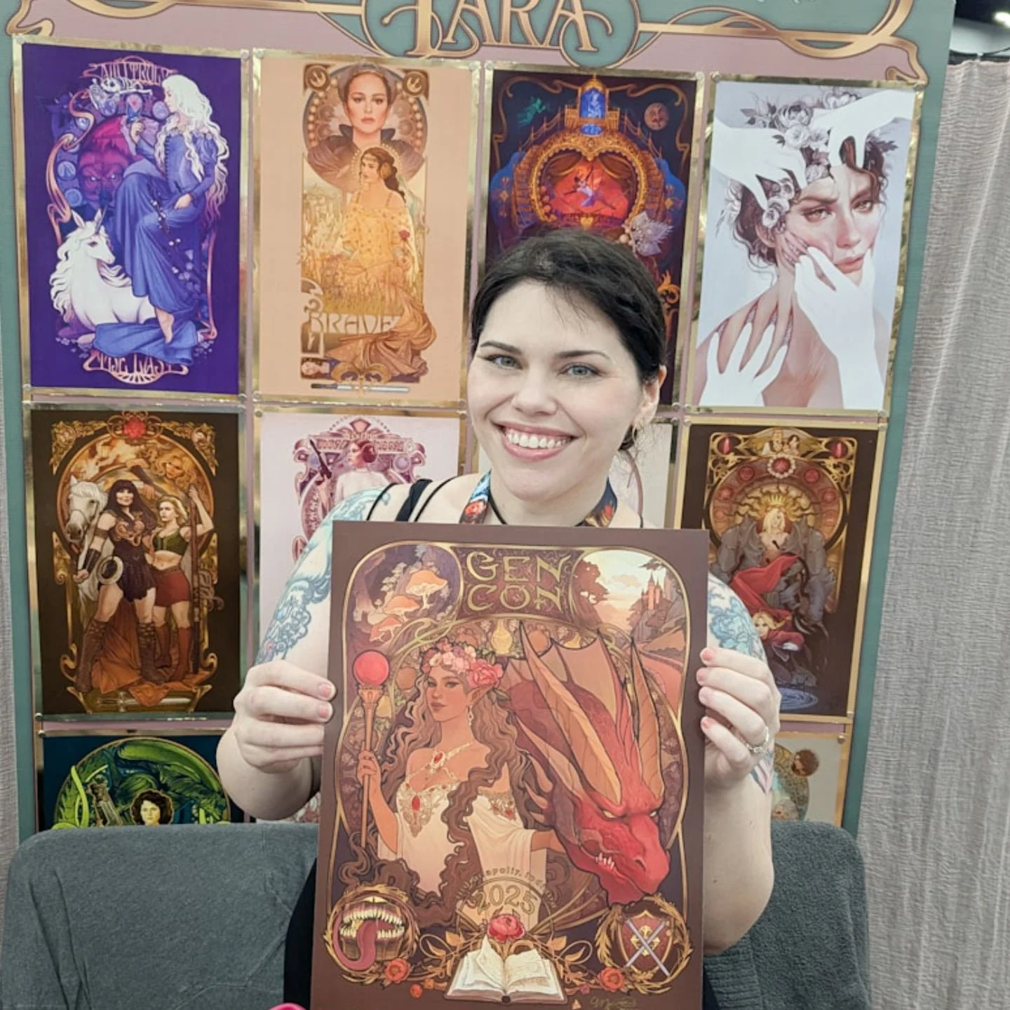 Here at table 35 in the art show at GenCon! I have foil prints of the program cover and other goodies &lt;3 some holo mimic stickers too 👀