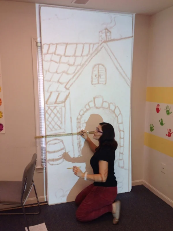 Miss Lorena tracing the sketch onto the periaktoi facing.