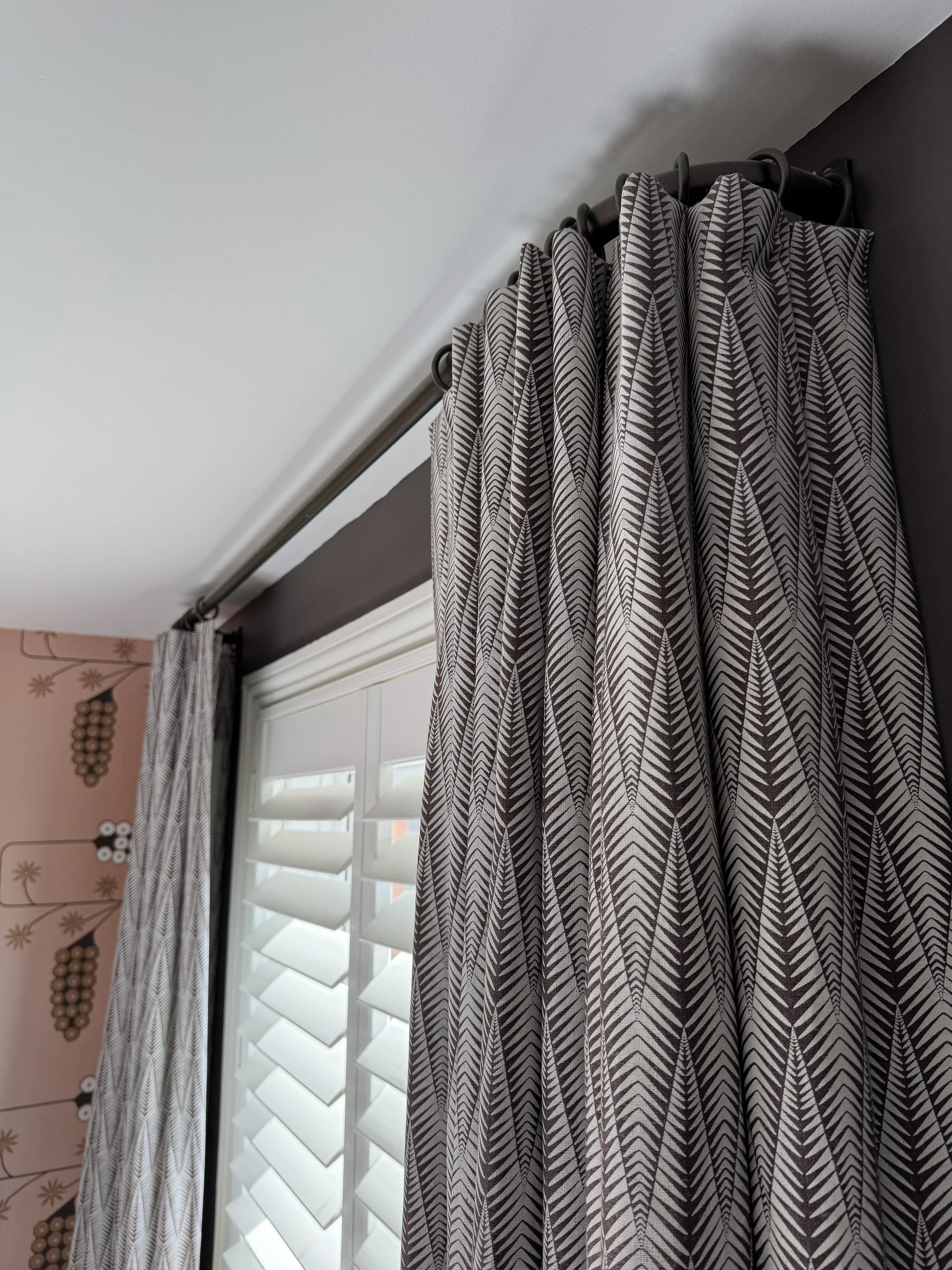 Close-up of Neisha Crosland Small Zebra curtains with plantation shutters and dark painted walls.