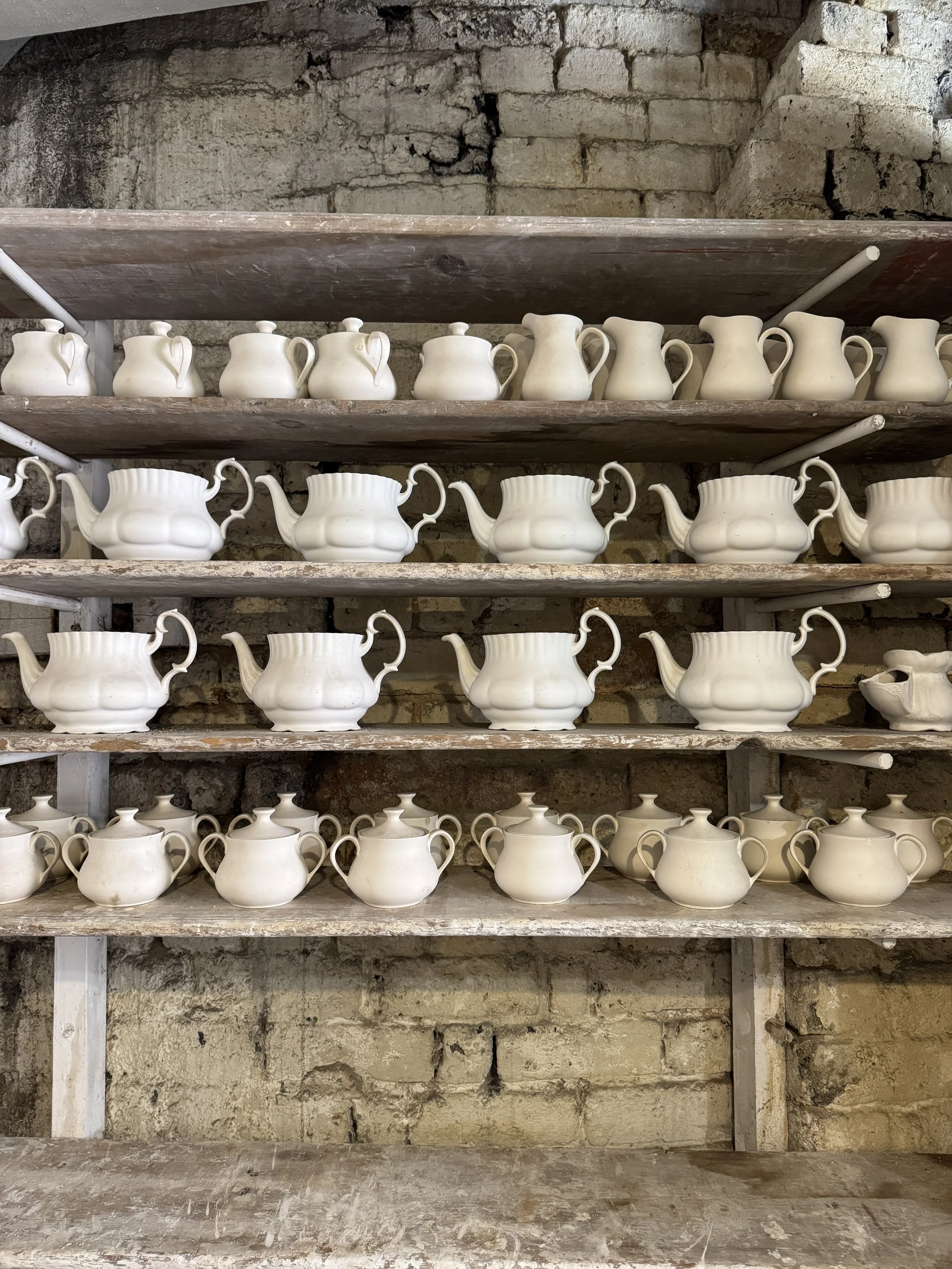Shelves of white teapots and jugs in a brick store, Gladstone Pottery Museum