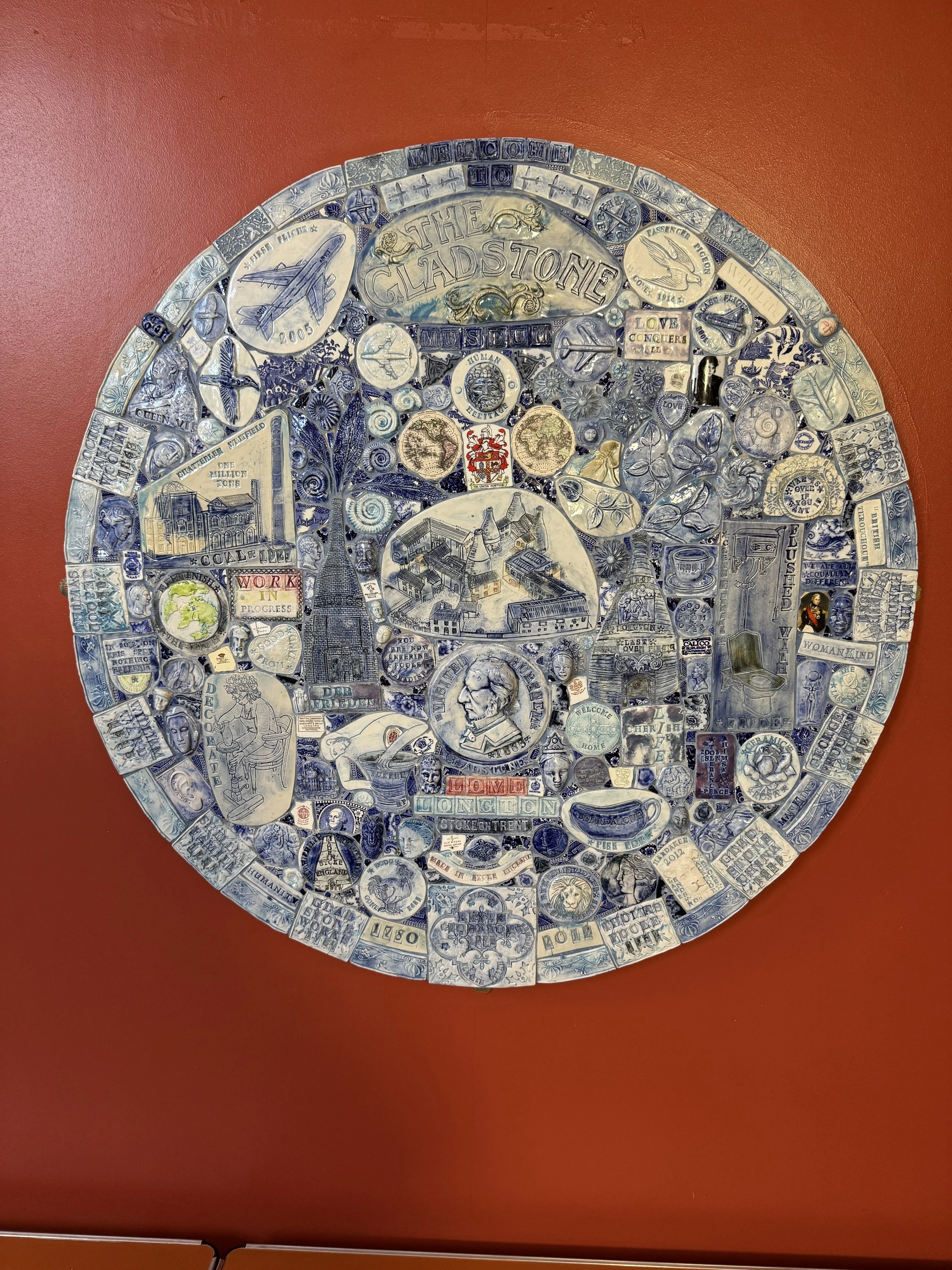 Round blue and white pottery mosaic on a red wall, Gladstone Pottery Museum