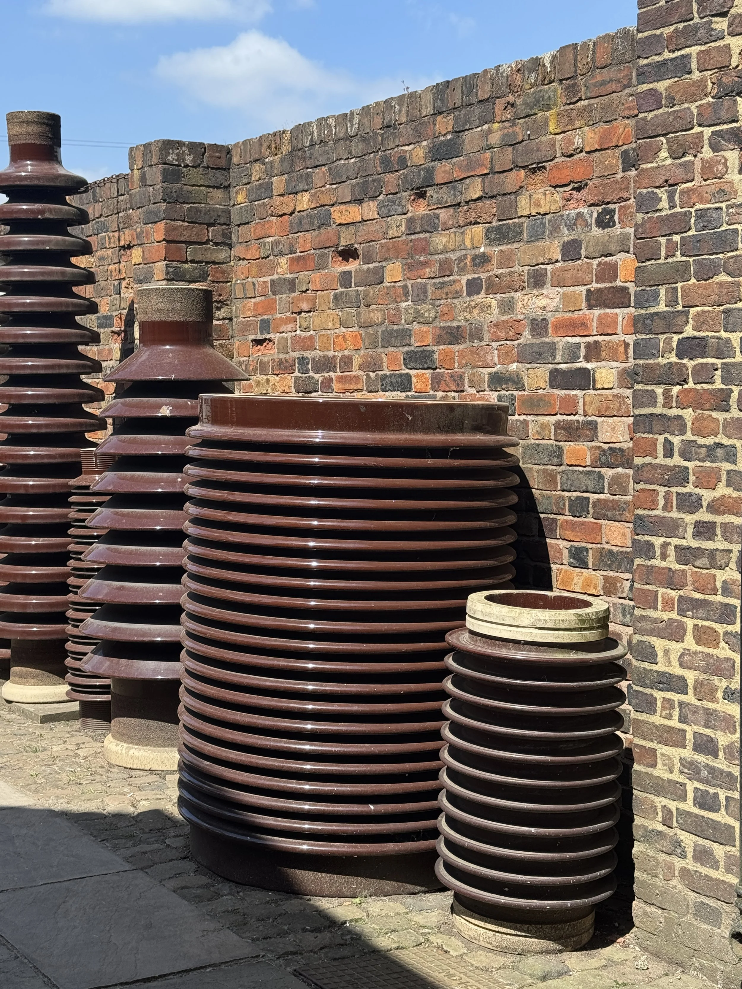 Glazed ceramic insulators stacked against a brick wall, Gladstone Pottery Museum