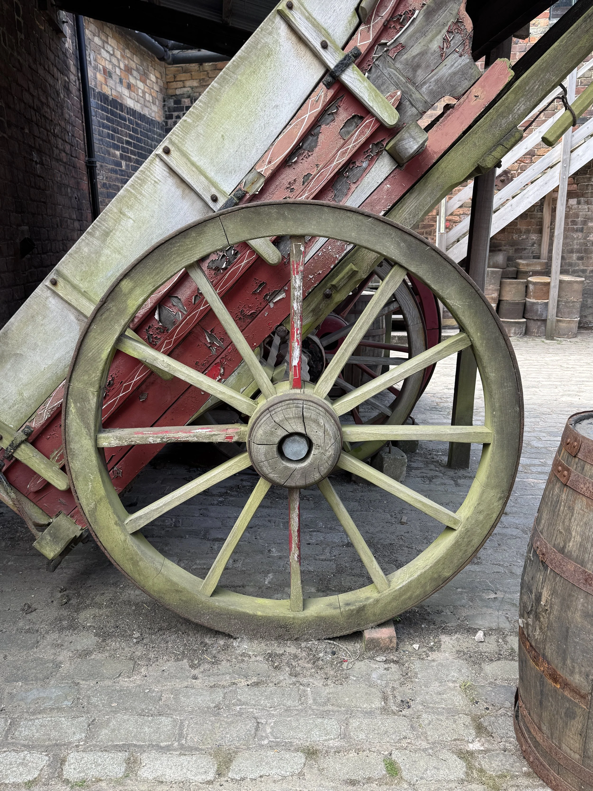 Old wooden cart wheel in the cobbled yard, Gladstone Pottery Museum